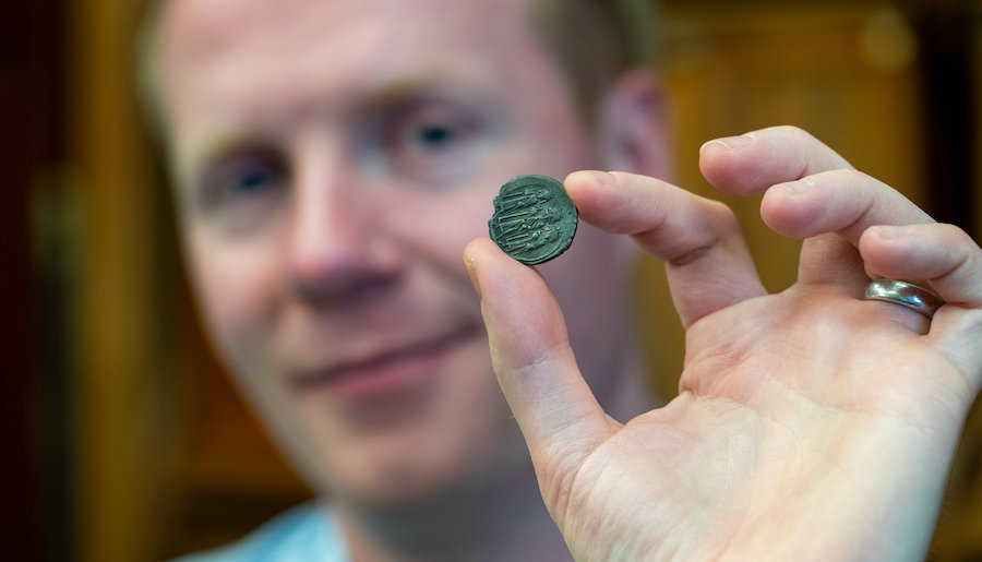 Professor Rory Naismith holding a Byzantine silver coin in the Fitzwilliam Museum.